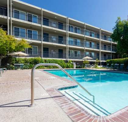 A swimming pool in front of a multi-story apartment building.